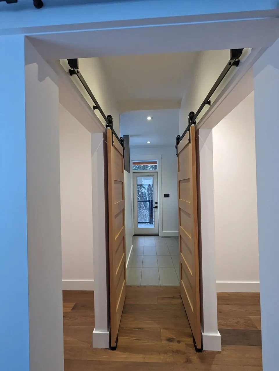 Hallway with white walls and natural wood barn doors