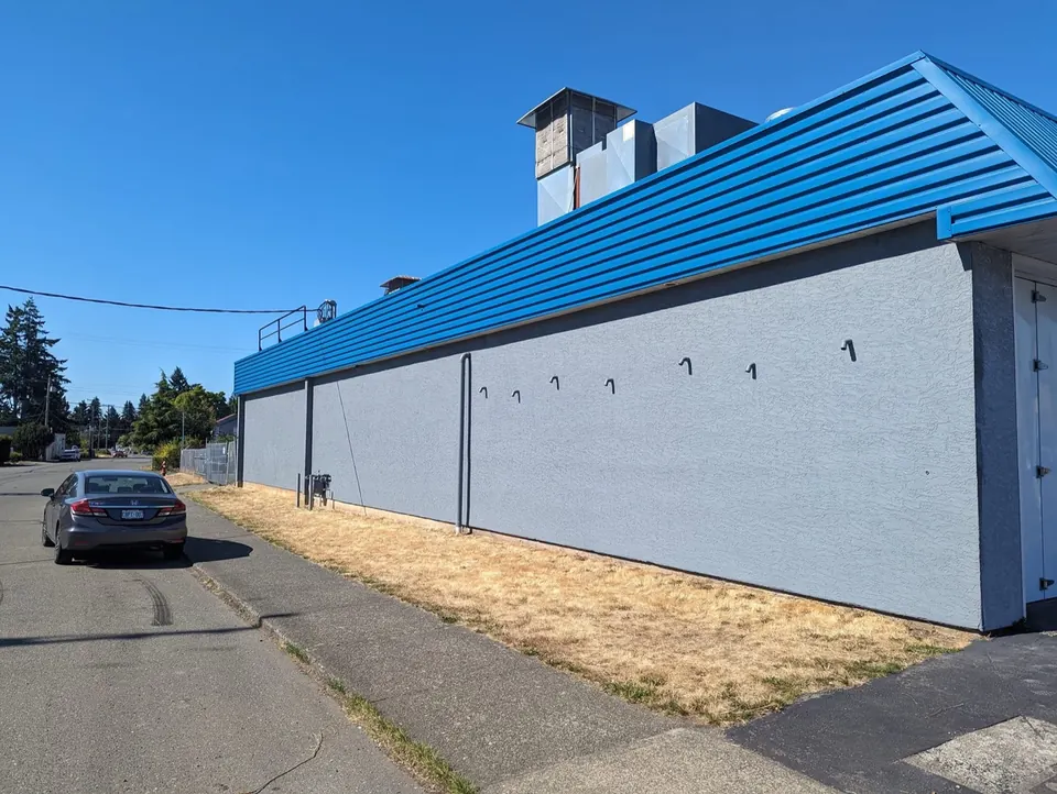 Long side wall of the shop, grey with a blue roofline