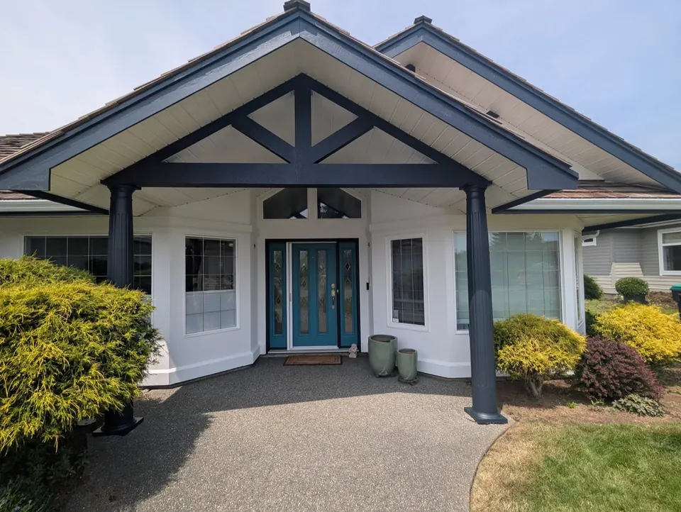 Covered entry with dark grey posts and a teal front door