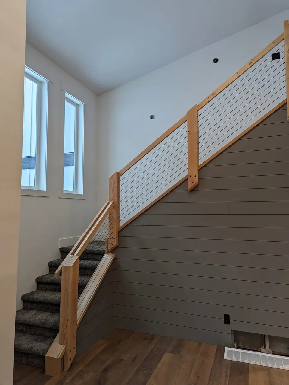 Stairwell with white walls and a stained wood railing